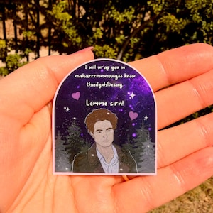 May include: A sticker with a purple and pink background featuring a male character illustration. The sticker has text that reads "I will wrap you in maharrrrmmmanoo know thadyuhlbesay. Lemme sirn!" with two purple hearts.