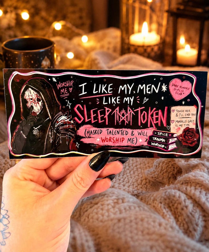 May include: A black and pink Sleep Token sticker with the text "I Like My Men Like My Sleep Token". The sticker features an illustration of a figure in a hooded cloak and a skull mask. Additional text includes "Dark Romance Girlie Club".