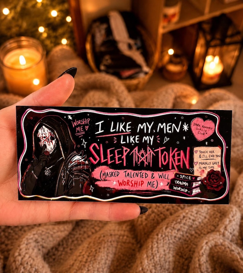 May include: Black rectangular sticker with the text "I LIKE MY MEN LIKE MY SLEEP TOKEN" and an illustration of a figure in a black hooded cloak. The sticker also includes the text "DARK ROMANCE GIRLIE CLUB".