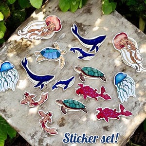 May include: A collection of colorful ocean-themed stickers featuring jellyfish, whales, turtles, and fish. The stickers are in various sizes and shapes, with a white border. The text "Sticker set!" is at the bottom.