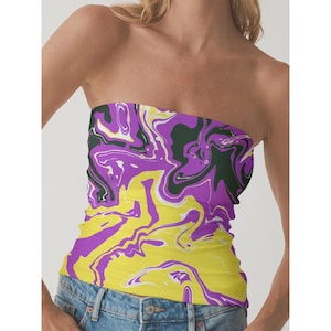 May include: A strapless tube top with a vibrant, abstract pattern. The design features swirling shades of yellow, purple, white, and dark green. The top is worn with blue denim jeans.