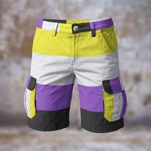 Puede incluir: Pantalones cortos cargo con diseño de la bandera del orgullo no binario. Los pantalones cortos presentan una combinación de colores amarillo, blanco, morado y negro. Tienen dos bolsillos cargo, cierre de botón y trabillas para el cinturón. Fabricados en tejido resistente.