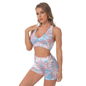 Könnte beinhalten: Ein zweiteiliges Sport-Set mit einem Batikmuster in Rosa, Blau und Weiß. Das Set besteht aus einem Sport-BH mit V-Ausschnitt und passenden High-Waist-Shorts. Der Stoff scheint strukturiert zu sein.