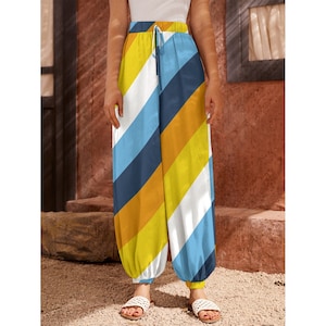May include: Wide-leg trousers with a diagonal striped pattern in yellow, white, blue, and orange. The trousers have a drawstring waist and elasticated cuffs at the ankles. The fabric is lightweight. The trousers are a vibrant, colourful design.