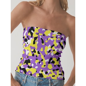 May include: A strapless tube top with a vibrant camouflage pattern. The design features irregular shapes in purple, yellow, black, and white. The top is made of a soft, stretchy fabric.