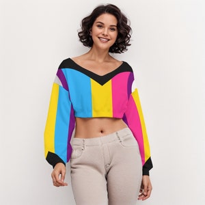 Peut inclure: Un pull court coloré avec un col en V noir. Le pull est rayé de jaune, rose, bleu et violet.