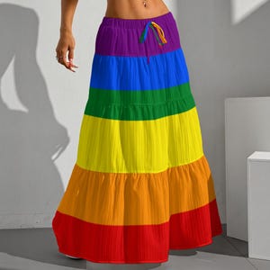 May include: A floor-length tiered skirt featuring horizontal stripes in a rainbow color sequence of purple, blue, green, yellow, orange, and red. The skirt has an elasticized waistband with a matching drawstring tie at the center front.