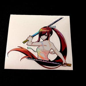 May include: A sticker featuring an anime-style illustration of a female character with red hair and two swords. The character is wearing a holographic top and has a determined expression.