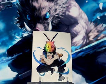 Può includere: Un adesivo con un'illustrazione colorata di un personaggio della serie anime Demon Slayer. Il personaggio è raffigurato con una maschera a testa di cinghiale con colori arcobaleno e dettagli blu. Lo sfondo mostra un'immagine più grande del personaggio con la testa di cinghiale.