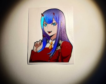 Può includere: Un adesivo con un personaggio anime con capelli blu e viola, occhi rossi e un vestito rosso e bianco. Il personaggio sorride e tiene una lecca-lecca.