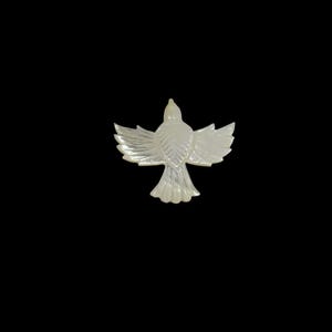 May include: A pearlescent white bird figurine with outstretched wings, set against a black background. The bird is carved with detailed feather patterns, showcasing a delicate and elegant design. The wingspan is approximately 2 inches.