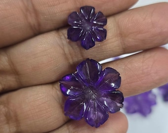 Könnte beinhalten: Zwei violette Amethyst-Blumencabochons. Die größere Blume hat einen Durchmesser von etwa 2,5 cm und die kleinere Blume einen Durchmesser von etwa 1,5 cm.