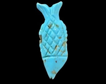 May include: A turquoise blue fish charm with a carved diamond pattern. The charm is made of natural turquoise and has a slightly rough texture.