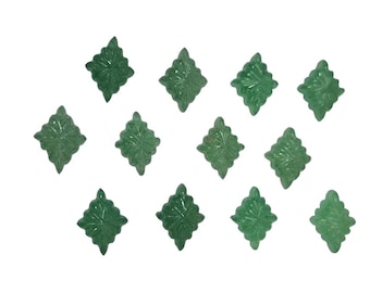 Puede incluir: Una colección de tallas de gemas verdes en forma de hoja. Cada talla presenta patrones detallados de venas de hojas y una forma de diamante. Las tallas están dispersas sobre un fondo blanco, mostrando su intrincado diseño.
