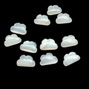 Könnte beinhalten: Zwölf weiße, wolkenförmige, irisierende Perlmutt-Cabochons. Die Cabochons sind glatt und poliert, mit einem subtilen Schimmer.