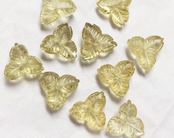 May include: Ten translucent yellow leaf-shaped gemstone carvings. The carvings are in the shape of a three-leaf clover.