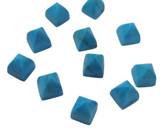 Puede incluir: Once cuentas de piedras preciosas turquesas, cada una con una base cuadrada y una parte superior piramidal, creando una forma geométrica. Las cuentas están dispersas sobre un fondo blanco. Cada cuenta mide aproximadamente 1 cm.
