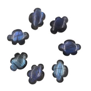 May include: Eight polished labradorite gemstone cloud carvings are displayed. Each cloud-shaped stone shows a mix of blue, grey, and iridescent colours. The carvings are arranged in a circular pattern against a white background.