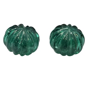May include: Two carved, green gemstone pumpkins. Each pumpkin has a ribbed texture and a stem. The gemstones are translucent, allowing light to pass through. The pumpkins are set against a white background.