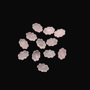 Peut inclure: Plusieurs pierres précieuses roses pâles en forme de nuage sont dispersées sur un fond noir. Chaque gemme présente une surface facettée, captant la lumière et créant un léger scintillement. Ces petites pierres décoratives sont idéales pour la création de bijoux ou les projets d'artisanat.