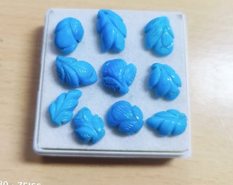 May include: A collection of ten turquoise cabochons, each carved in the shape of a leaf, displayed in a white box.