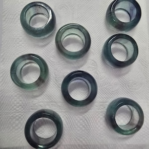 Op de afbeelding: Tien groene en blauwe edelsteenringen met een gladde, gepolijste afwerking. De ringen zijn allemaal van verschillende grootte en vorm, maar ze hebben allemaal een vergelijkbaar ontwerp.