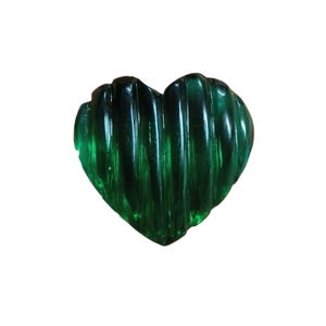 May include: A heart-shaped, emerald green glass object. The glass has a ribbed texture, creating vertical lines across the surface. The object is a solid, translucent green, with a glossy finish.