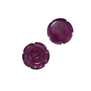 May include: Two carved rose-shaped gemstones in a deep magenta hue. One rose is fully detailed with petals, while the other is a simpler, rounded design. The gemstones are set against a plain white background.