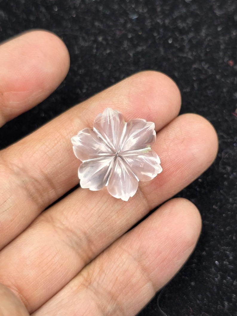 K&ouml;nnte beinhalten: Eine klare Quarzblume, die in Form einer zarten Blume geschnitzt ist. Die Blume hat f&uuml;nf Bl&uuml;tenbl&auml;tter und einen Mittelpunkt.