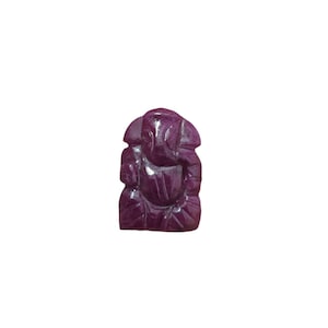 May include: A carved, deep purple figurine of the Hindu deity Ganesha. The sculpture is detailed, with visible lines and curves defining the elephant-headed god's form. The figurine is set against a plain white background.