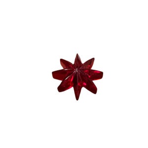 May include: A faceted, star-shaped decorative object in a deep red hue. The object has eight pointed tips radiating from a central point. The material appears to be translucent, catching the light and creating a sparkling effect. The object is isolated on a white background.