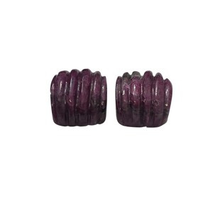 May include: Two carved, dark purple gemstone beads. Each bead has a ribbed design and a square shape. The beads are displayed against a white background. The gemstones appear to be polished.