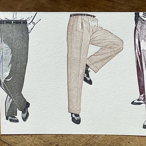 May include: Three pairs of pants illustrated on a white card. The pants are in different colors and styles. The pants on the left are dark gray, the pants in the middle are beige, and the pants on the right are burgundy.