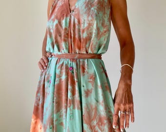 May include: A sleeveless halter-neck maxi dress featuring a tie-waist belt and a marbled pattern in shades of mint green and terracotta. The fabric is adorned with small, scattered sequins and occasional embroidered floral accents.