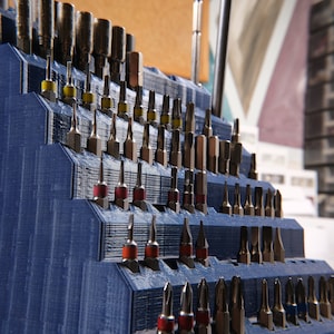 Op de afbeelding: Een blauwe plastic organizer met een verscheidenheid aan schroevendraaierbits. De organizer is gevuld met verschillende maten en soorten bits, waaronder Phillips, platte kop en Torx.