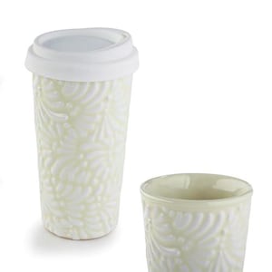 Puede incluir: Una taza de viaje de cerámica de color amarillo pálido con tapa de silicona blanca y una taza abierta a juego, ambas con un patrón de hojas en relieve en la superficie exterior. El diseño consiste en formas orgánicas curvas.