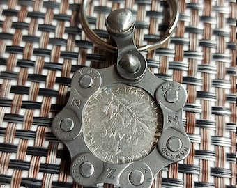 Portachiavi con moneta da un franco del 1991, ciondolo ricavato da una catena di bicicletta riciclata.