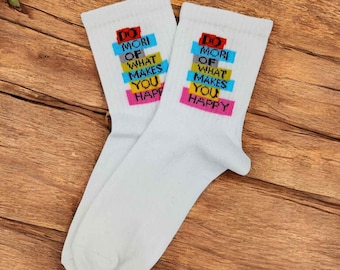 May include: A pair of white socks with a colorful slogan that reads "Do more of what makes you happy".