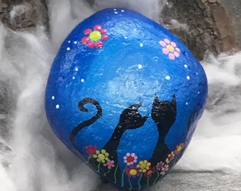 The Spring Cats/Lucky Cats are here. Motif #5, hand-painted on a blue background on an oval/round natural stone.