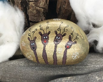 Osiem (8) reniferów na złotym okrągłym kamieniu naturalnym. Z każdej strony witają Cię 4 renifery „Pebble Art”, ręcznie malowane na kamieniu naturalnym.
