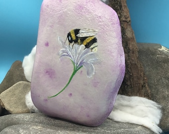 The bumblebees are on the loose. Bumblebee on the flower hand-painted in watercolor style and immortalized on a natural stone/river stone