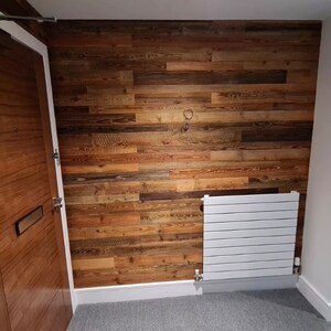 May include: A hallway with a wooden door, a white radiator, and a wall covered in reclaimed wood panels.