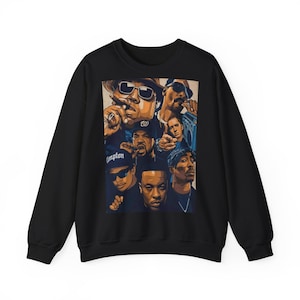 Peut inclure: Sweat-shirt noir à col rond avec un collage d'artistes hip-hop dans des tons de marron, beige et bleu. Le graphisme comprend des portraits de plusieurs musiciens. Le mot "Compton" est visible sur un chapeau.