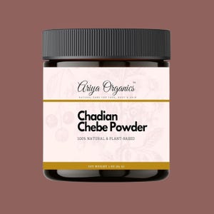 May include: A brown glass jar with a black lid containing Chadian Chebe Powder. The label is white with black text and a floral design. The text on the label reads "Ariya Organics", "Natural Care for Face, Body & Hair", "Chadian Chebe Powder", "100% Natural & Plant-Based", and "Net Weight 1 oz (83 g)".