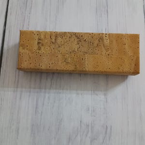Könnte beinhalten: Eine rechteckige Korkbox in natürlicher brauner Farbe mit leicht rauer Textur.