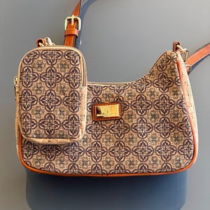 Pode incluir: Uma bolsa de mão marrom e bege estampada com uma bolsa menor combinando anexada. A bolsa de mão tem uma alça de couro marrom e um detalhe de metal dourado.