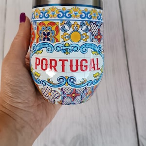 Op de afbeelding: Een roestvrijstalen reisbeker met een decoratief Portugees tegelontwerp. De beker heeft een witte achtergrond met kleurrijke bloemen- en geometrische patronen en het woord "PORTUGAL" in het rood.