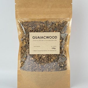 May include: A clear plastic bag filled with cut and dried guaiacwood bark, with a brown paper backing. The label reads "GUAIACWOOD" and "net weight 100g". The bag is sealed and ready for use.