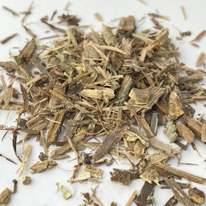 以下が含まれることがあります： 白い表面に置かれた、乾燥した薄茶色と緑色の植物質の塊。ハーブや根っこと思われる。