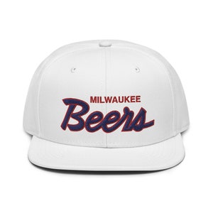 Puede incluir: Gorra de béisbol blanca con un logotipo bordado en azul marino y rojo que dice "MILWAUKEE Beers".